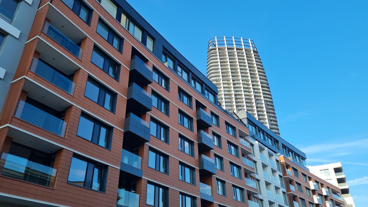Modern urban apartment buildings with a skyscraper under a clear blue sky, showcasing architectural design.