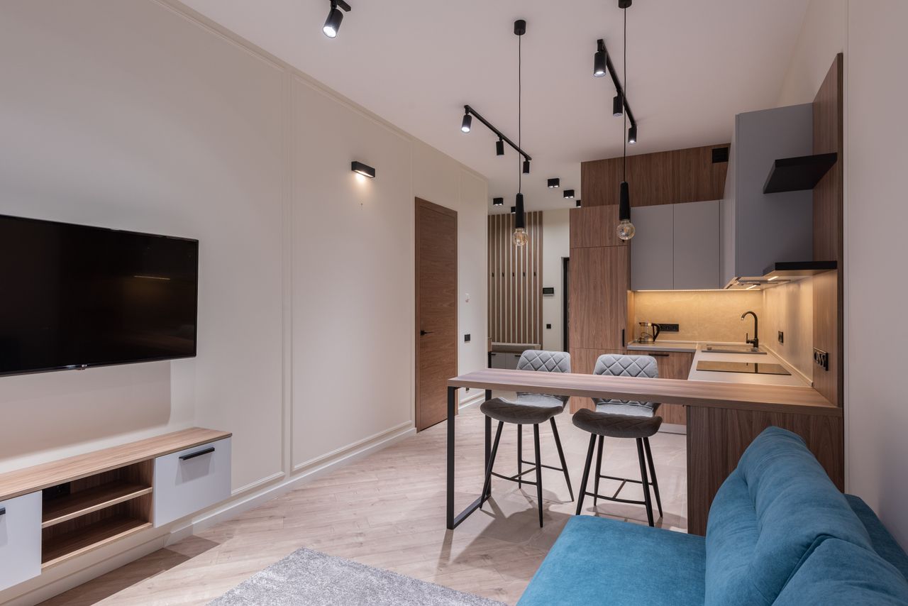 Interior of modern studio with kitchen furniture dining area and lounge with blue sofa